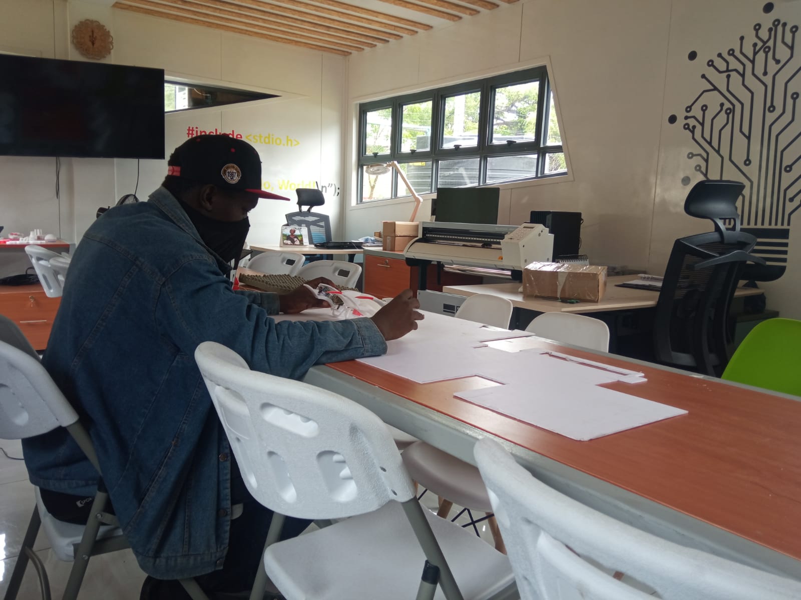 Our workspace with a cutting plotter, printed parts and a client at the table